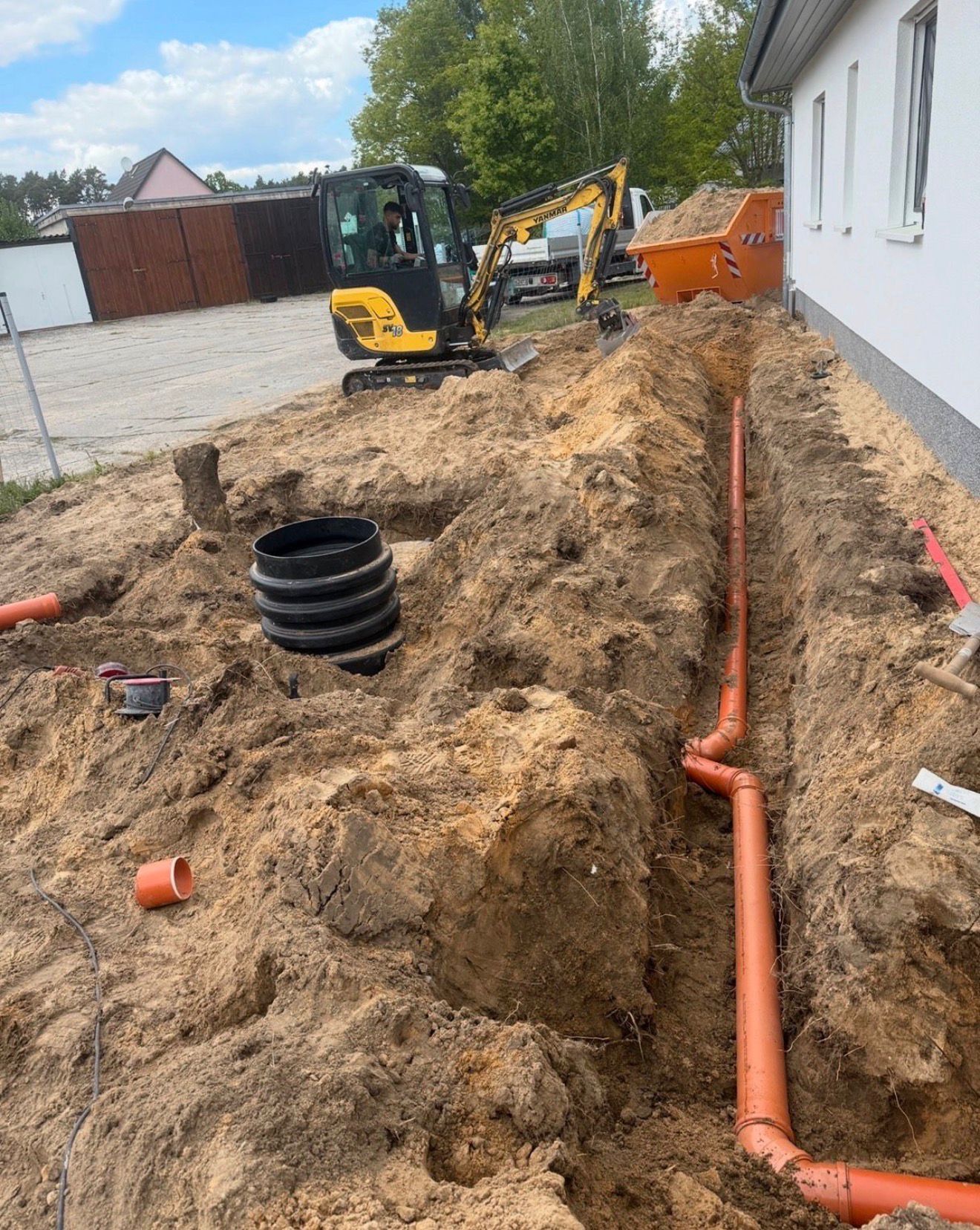 Bagger bei der Verlegung des Rohrgrabens neben einem Wohnhaus